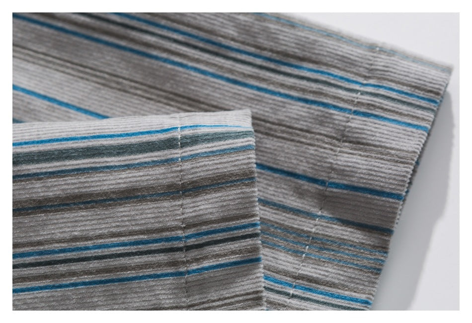 Close-up of gray fabric with blue and charcoal stripes, showing overlapping stitched garment edges.