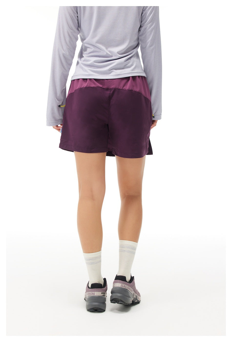 Rear view of a model wearing plum athletic shorts with a contrasting pink waistband panel.