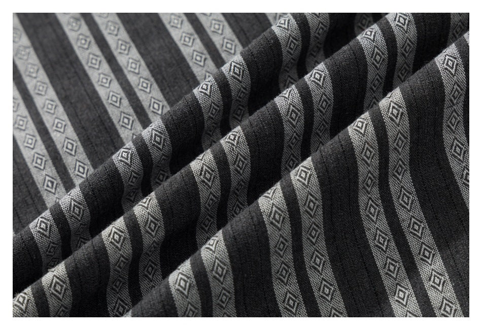 Close-up of the gray shirt fabric draped into folds, showing dark stripes and small diamond motifs.