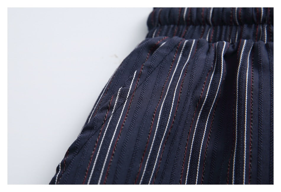 Close-up of the elastic waist and a seam on dark navy fabric with fine white and muted red stripes.
