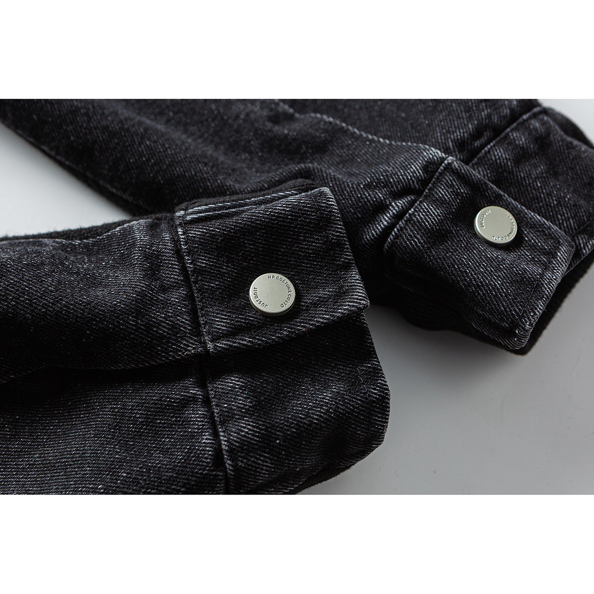 Close-up of black jacket cuffs with round silver-tone buttons and visible stitching.