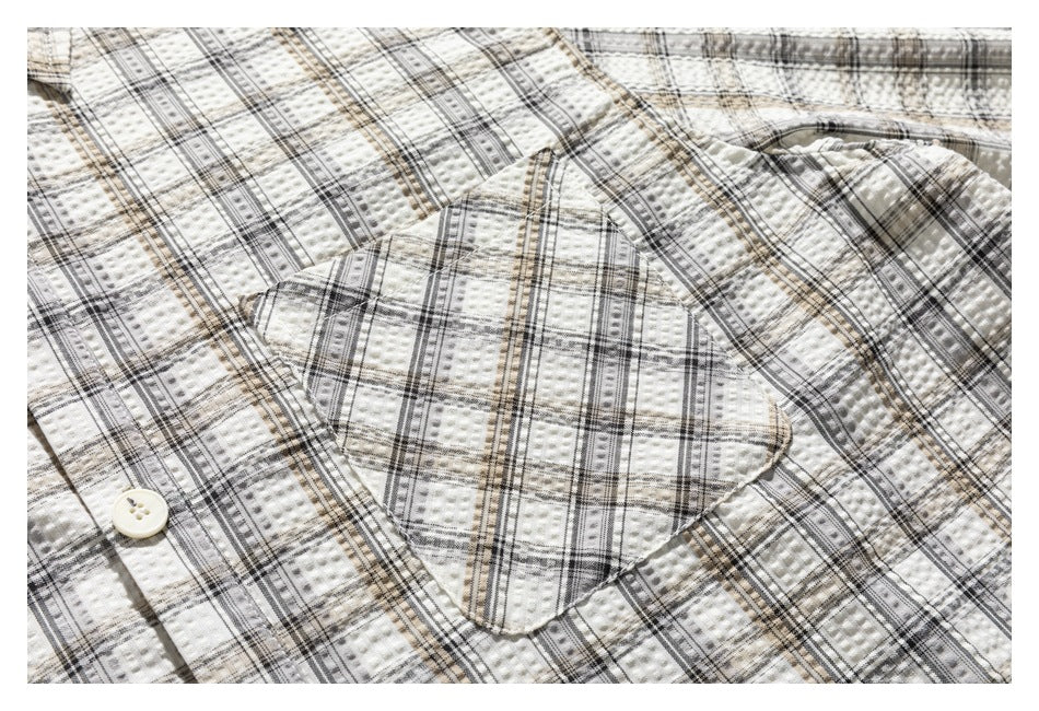 Close-up of a square chest pocket on the cream plaid shirt.