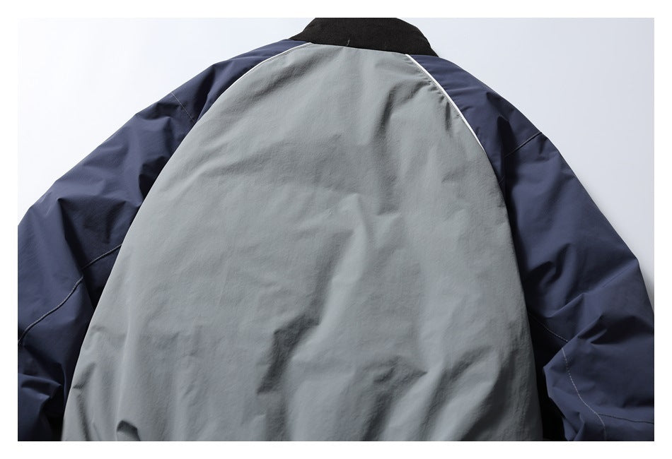 Back view of a jacket with a light gray body panel, navy sleeves, black collar, and white piping.