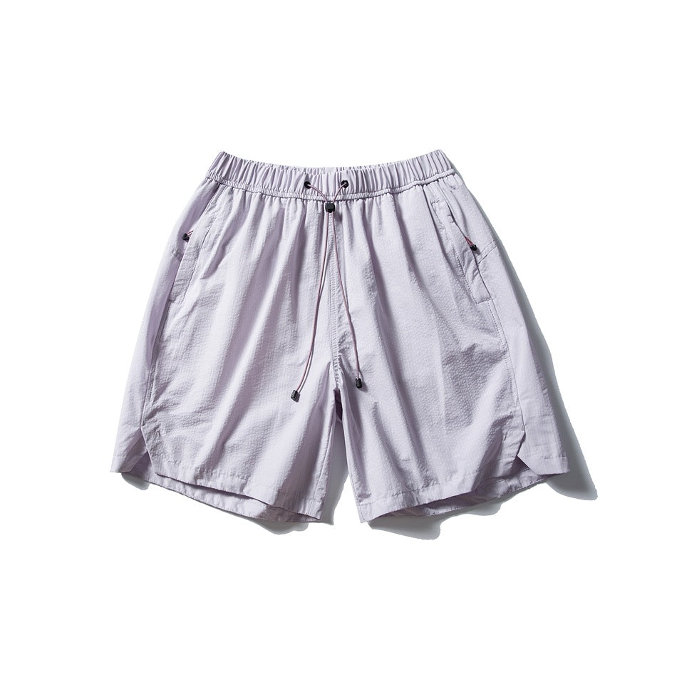 Light lavender drawstring shorts with elastic waistband, side pockets and curved side-slit hems, flat lay