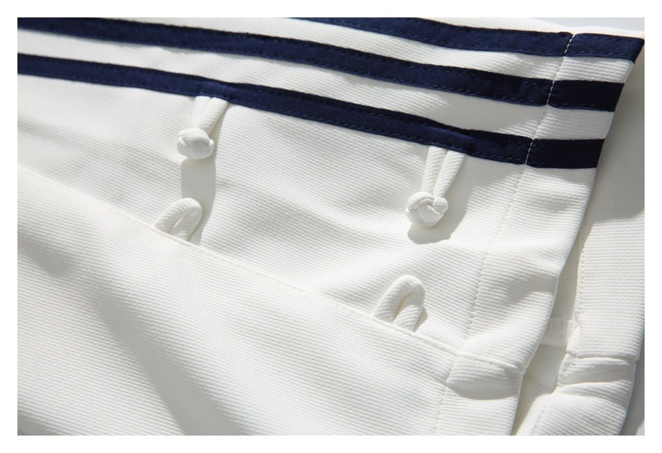 Close-up of a white trouser pocket, navy stripes, and knotted white fasteners.