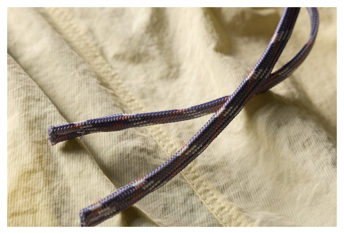 Close-up of braided lavender drawcords crossing pale yellow patterned fabric.