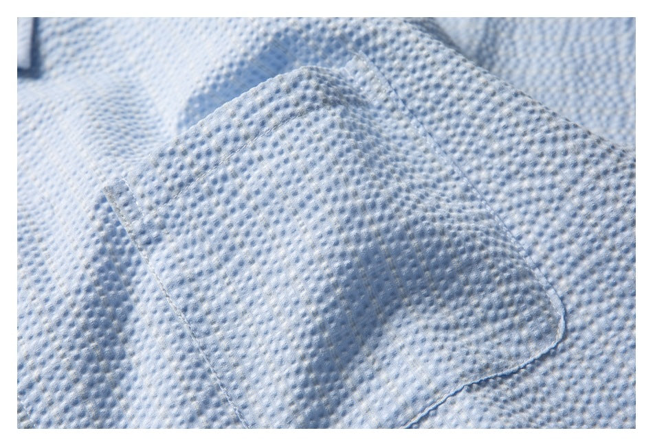 Close-up of the pale blue textured shirt's stitched patch pocket.