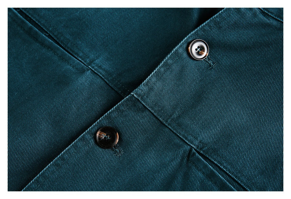 Close-up of dark buttons, stitching, and diagonal seams on the teal jacket.