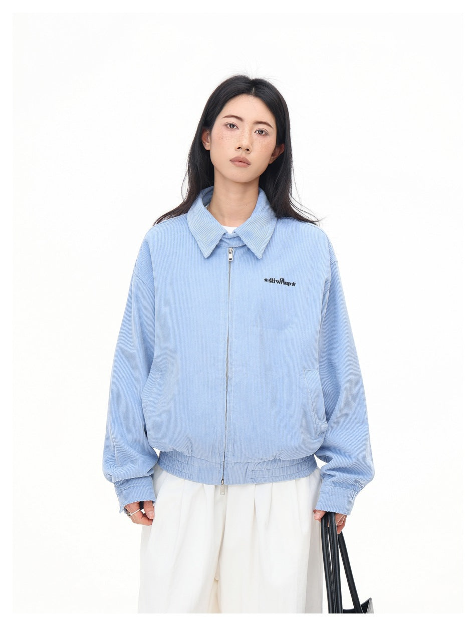 Front view of a model in a light blue collared jacket with a front zipper, elastic hem, and small black chest lettering.