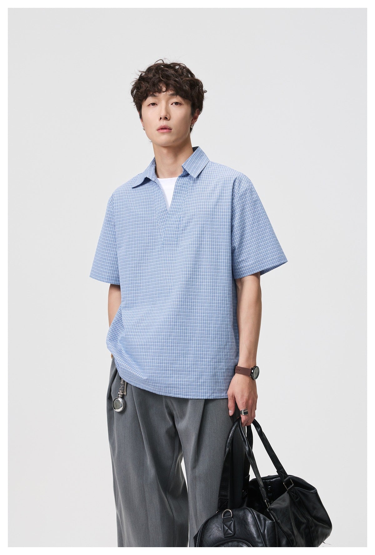 Man modeling the front of a blue-and-white micro-check short-sleeve collared shirt.