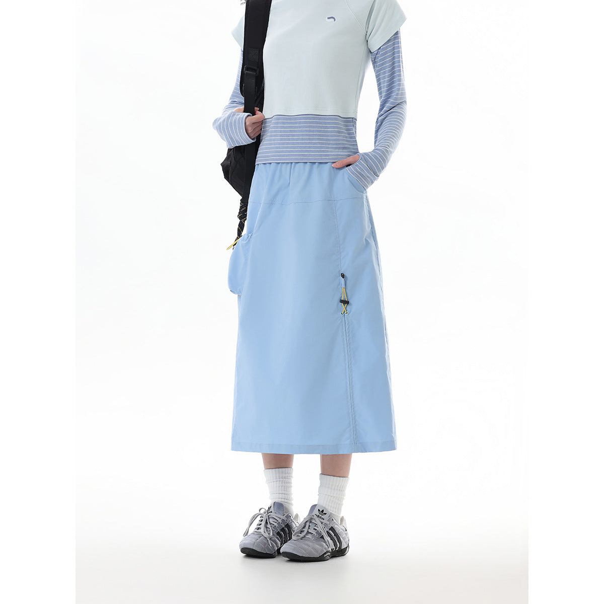 Front view of a model wearing a light blue midi skirt with side pockets and a striped layered top.