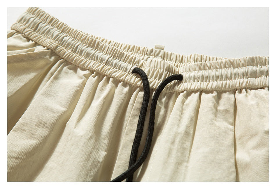 Close-up of cream shorts with a gathered elastic waistband and black drawstring.