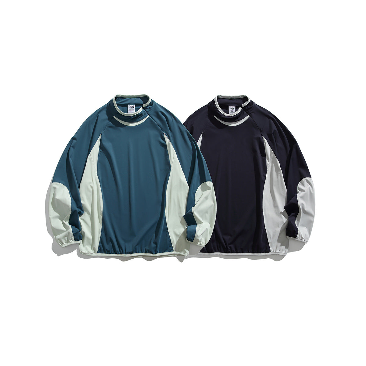 Two long-sleeve colorways of a high-neck pullover: teal with pale panels and dark navy with pale panels.