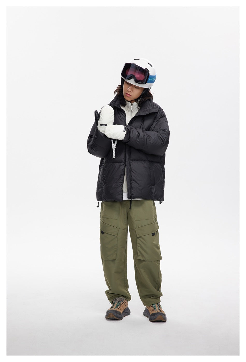 Model wearing a black puffer jacket with a high collar, shown full length in ski gear.