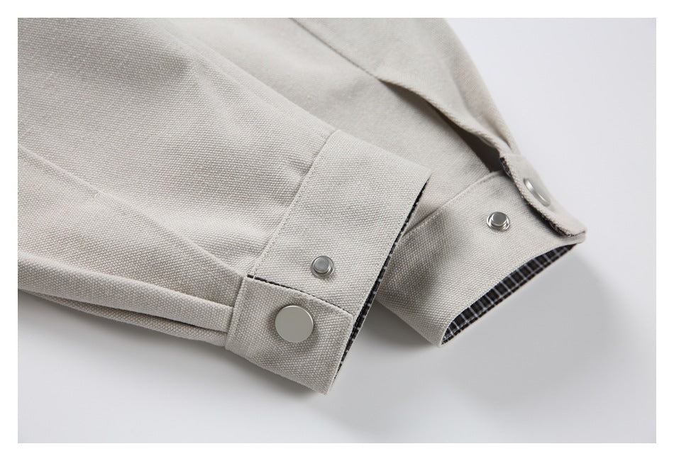 Close-up of beige jacket cuffs with adjustable snap tabs and checked lining visible inside.