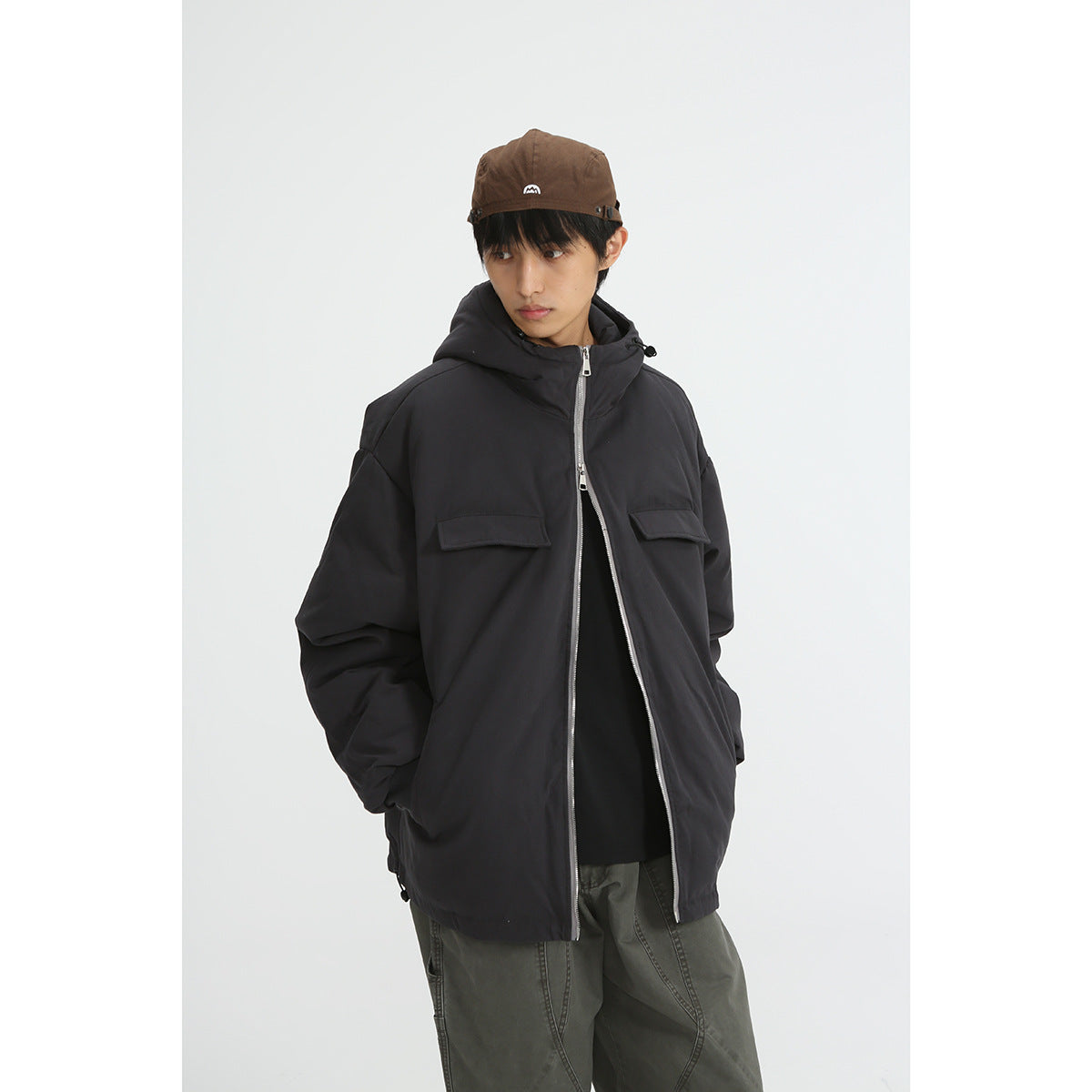 Model wearing a black hooded jacket with a silver front zipper and flap chest pockets.