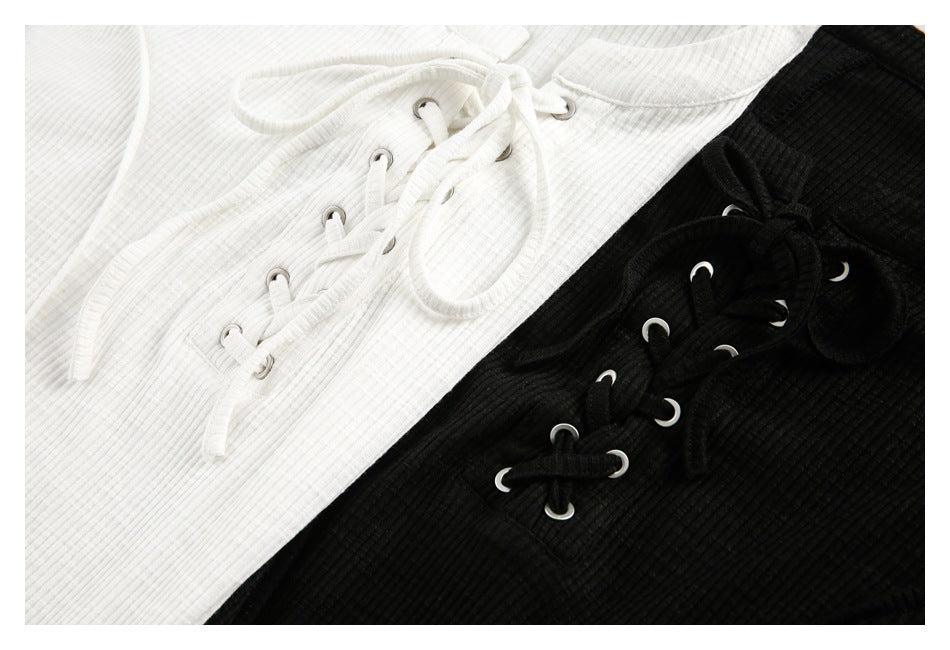 Close-up of white and black ribbed tops showing their lace-up fronts, eyelets, and matching ties.