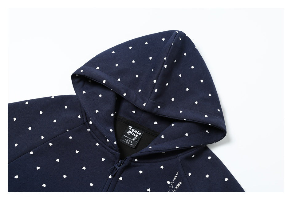 Close-up of a navy hoodie hood and shoulder with small white hearts, zipper, and black neck label.