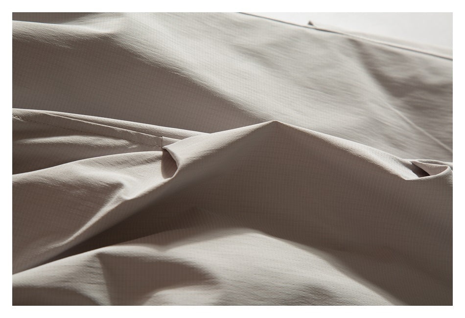 Close-up of taupe fabric folds with a stitched seam and a small folded edge.