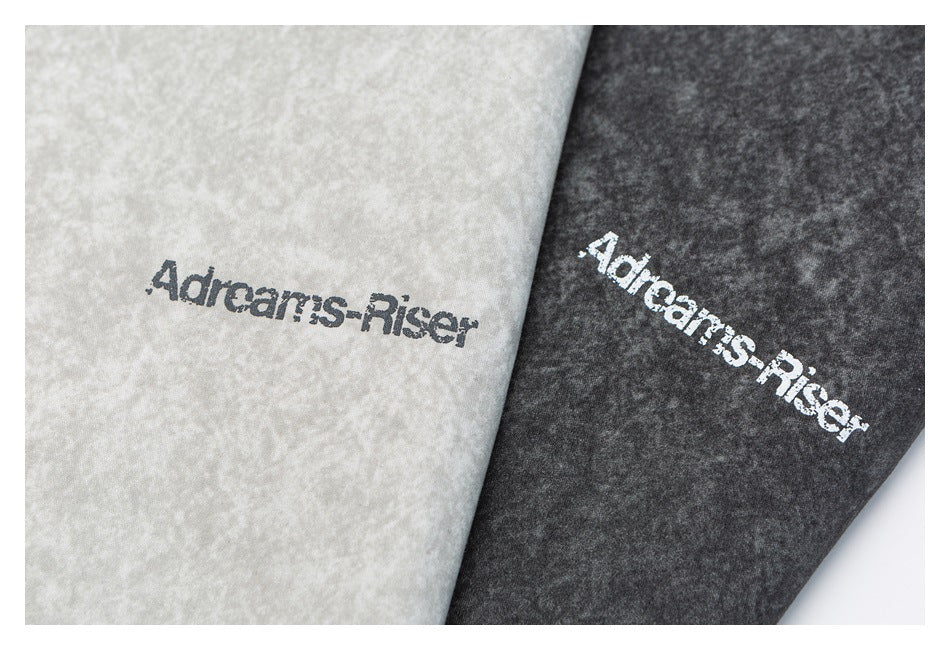 Close-up of the garment lettering printed on light gray and charcoal mottled shirt fabric.