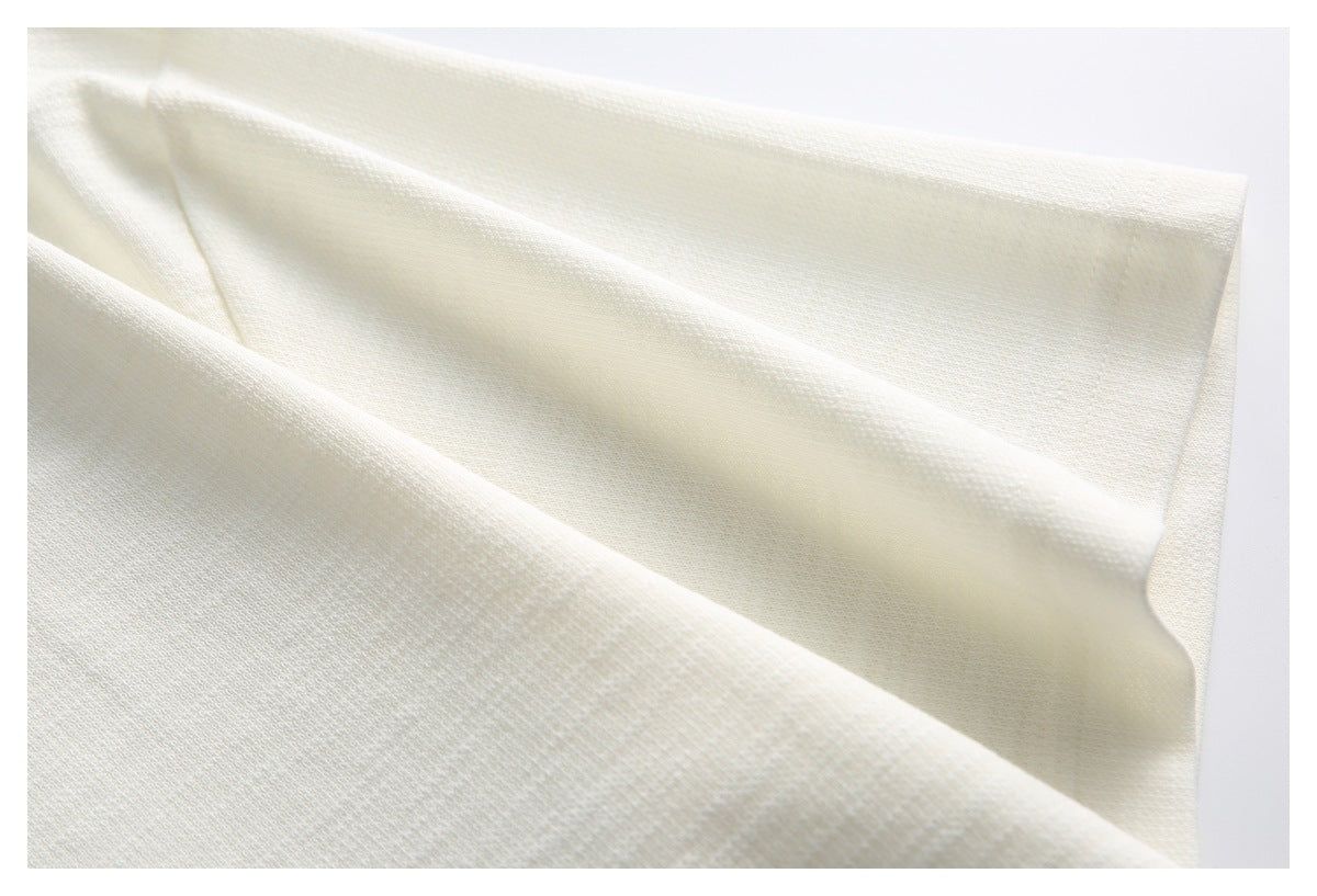 Close-up of the ivory garment's textured knit fabric and folded edge.
