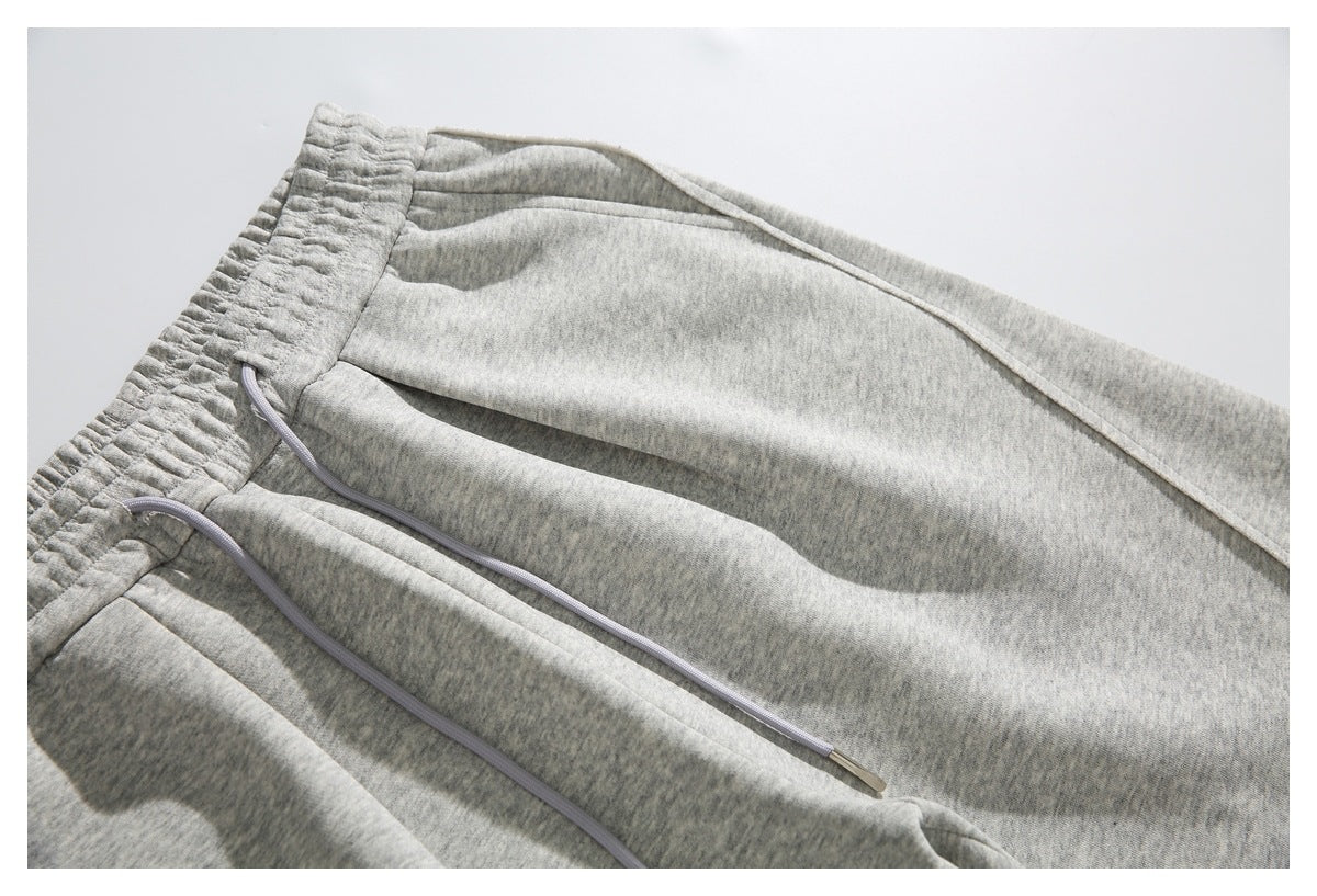 Close-up of light gray heather sweatpants with an elastic waistband and long drawstrings.