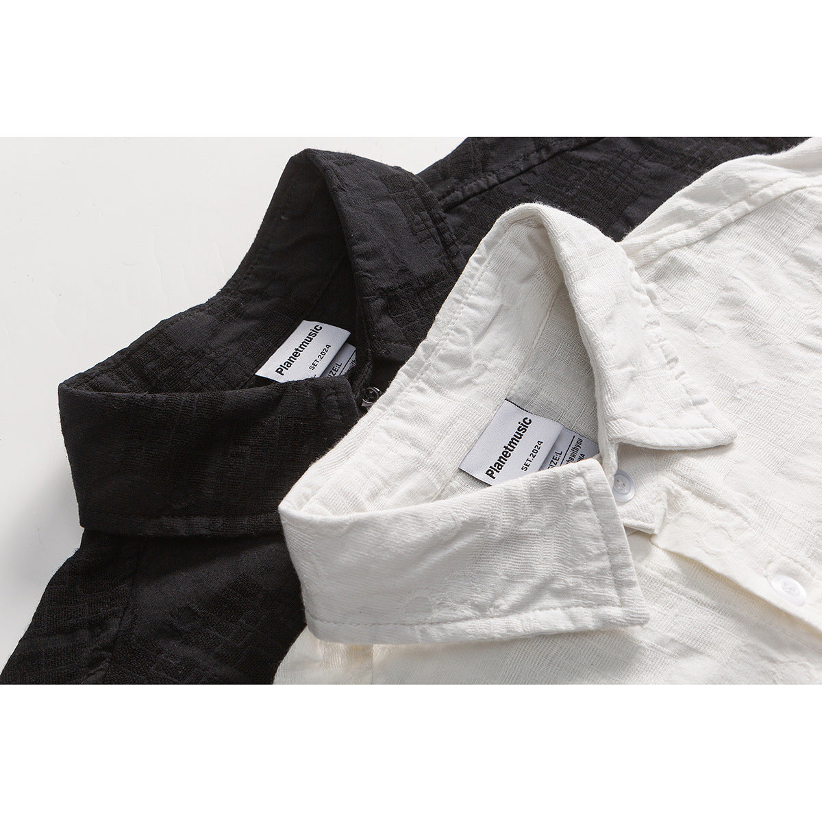 Close-up of black and white textured short-sleeve shirts showing their collars, buttons, and neck labels.