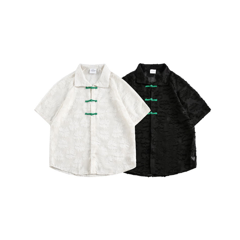 White and black short-sleeve collared shirts shown flat, each with raised floral texture and green frog closures.