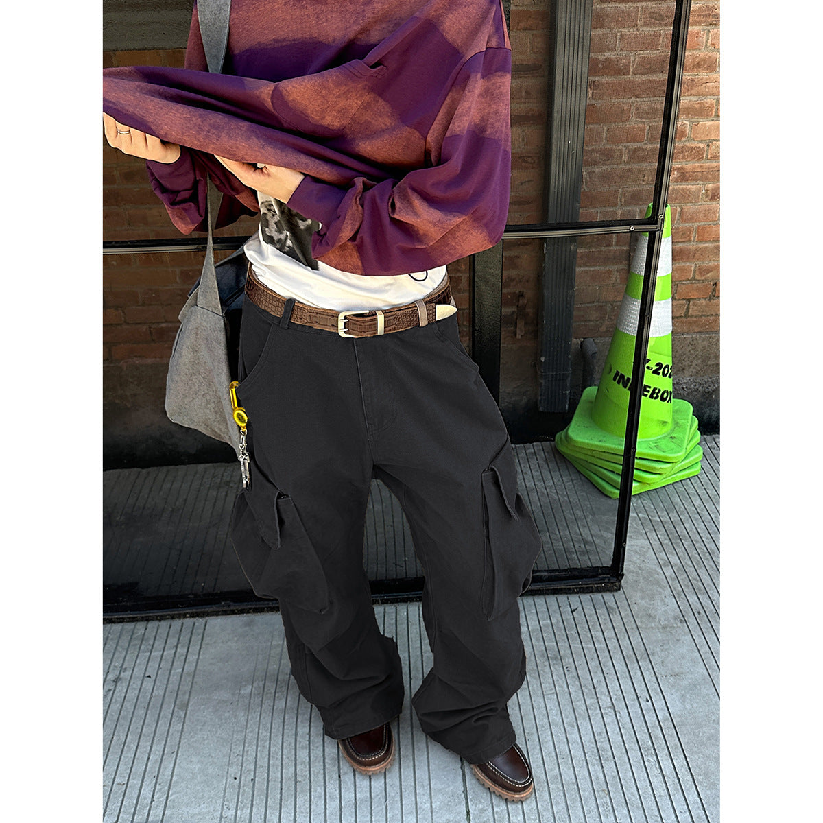 Cropped model wearing loose black cargo pants with large flap pockets and a purple patterned top.
