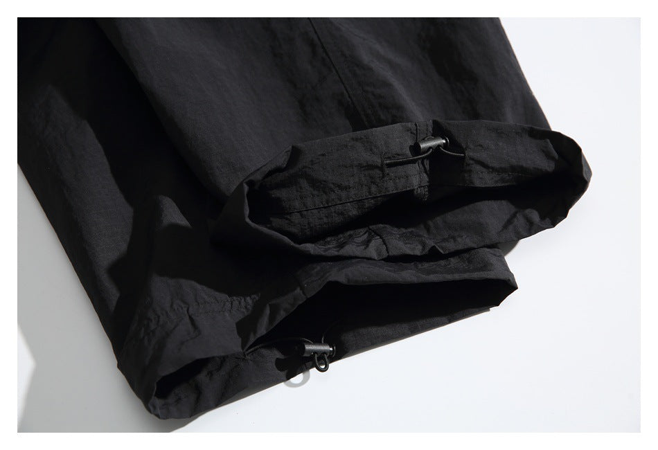 Close-up of a black pant leg hem with adjustable drawcords and cord locks.