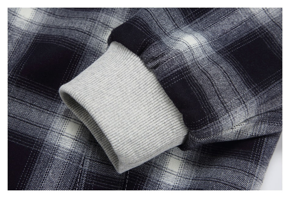 Close-up of a light gray ribbed cuff on a black, gray, and white plaid sleeve.