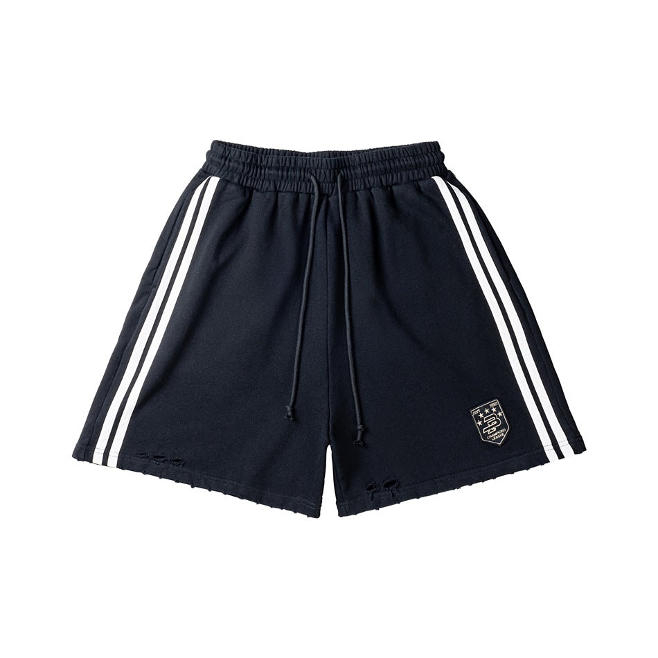 Black drawstring shorts with white double side stripes, shield patch and distressed hems, flat lay front view