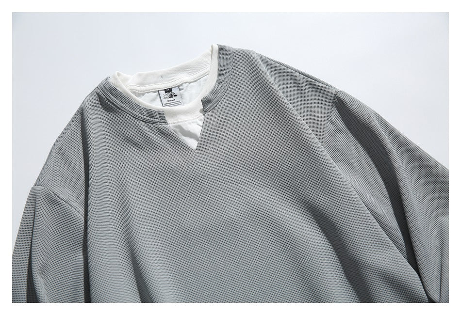 Close-up of the gray textured top's notched neckline and white undershirt layer.