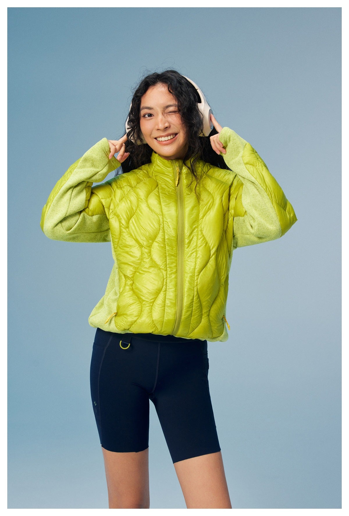 A model wears a lime-green quilted zip jacket with contrasting sleeves and a high collar.