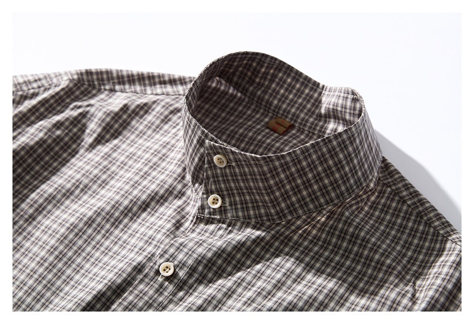 Close-up of a gray, black, and cream checked shirt collar with cream buttons.