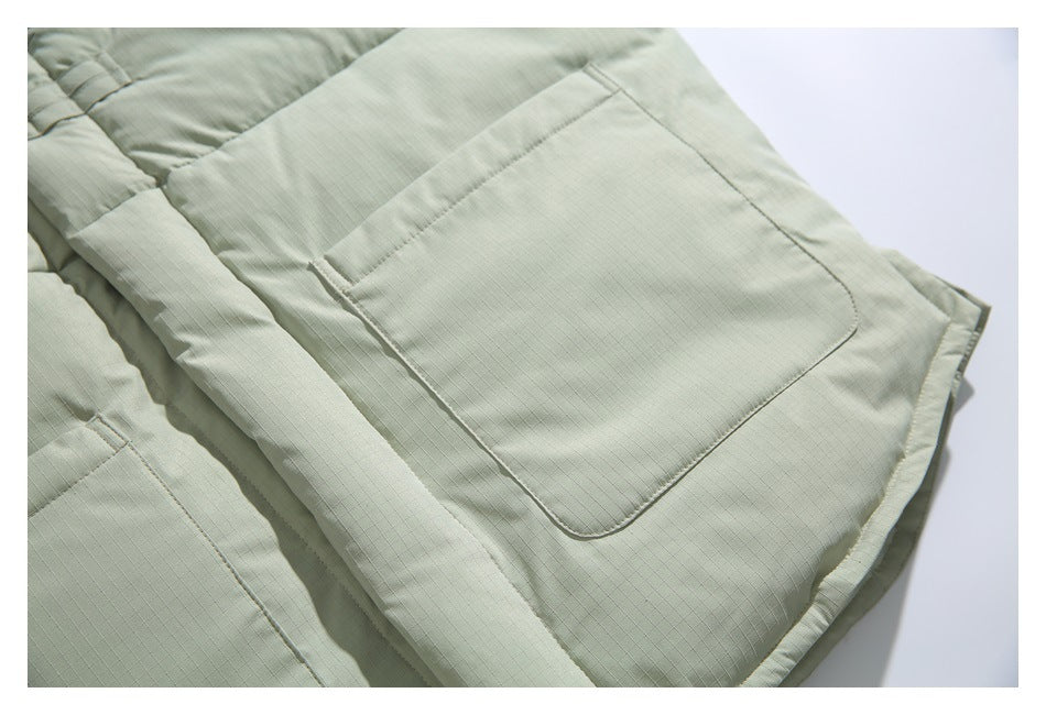 Close-up of a large square pocket on the pale sage jacket, with stitched edges and front placket.