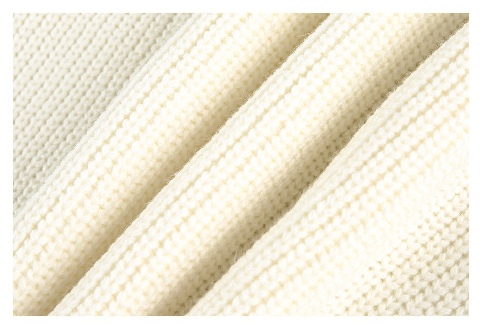 Close-up of ivory knit fabric with a chunky, textured stitch pattern.