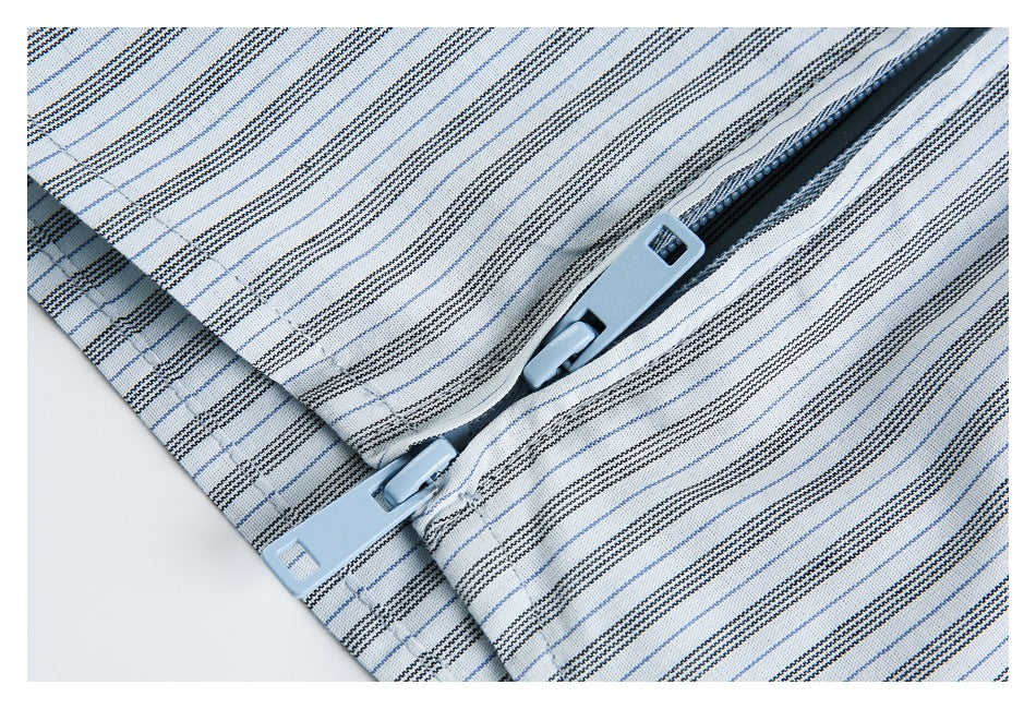 Close-up of a pale blue zipper set into white fabric with fine blue and dark stripes.