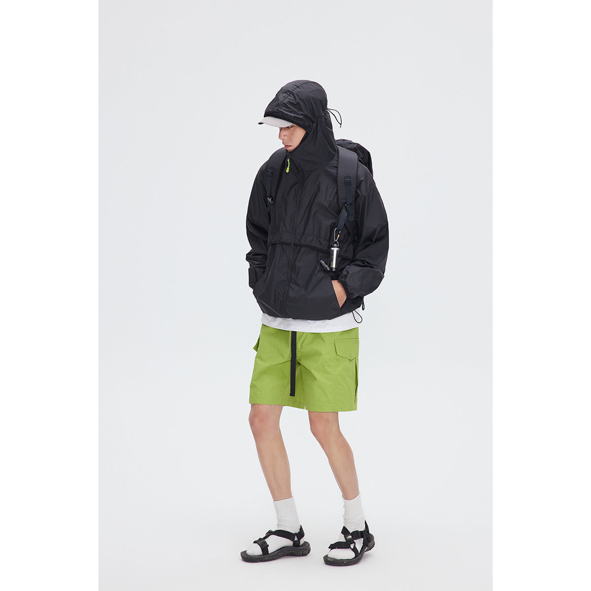 Model wearing a black hooded jacket with a high collar and bright green zipper pull.