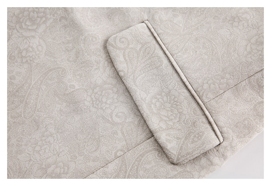 Close-up of a flap pocket and piped edge on the pale beige paisley blazer.