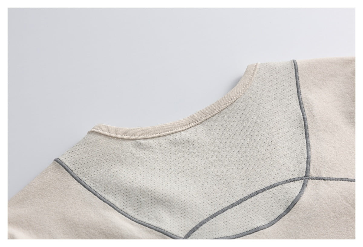 Close-up of a beige garment's perforated mesh panel, rounded bound edge, and gray curved seams.