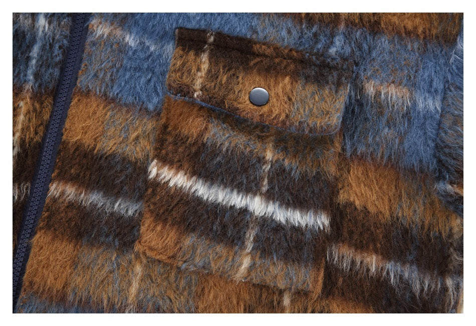 Close-up of a flap pocket with a dark snap on the fuzzy plaid jacket beside its zipper.