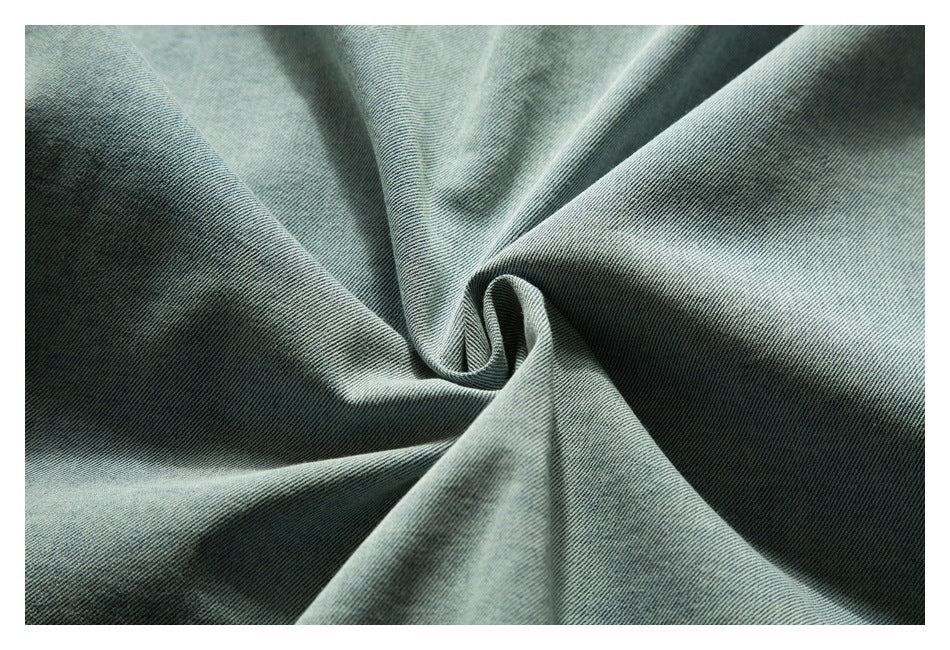 Close-up of light blue denim fabric gathered into folds, showing its diagonal weave.