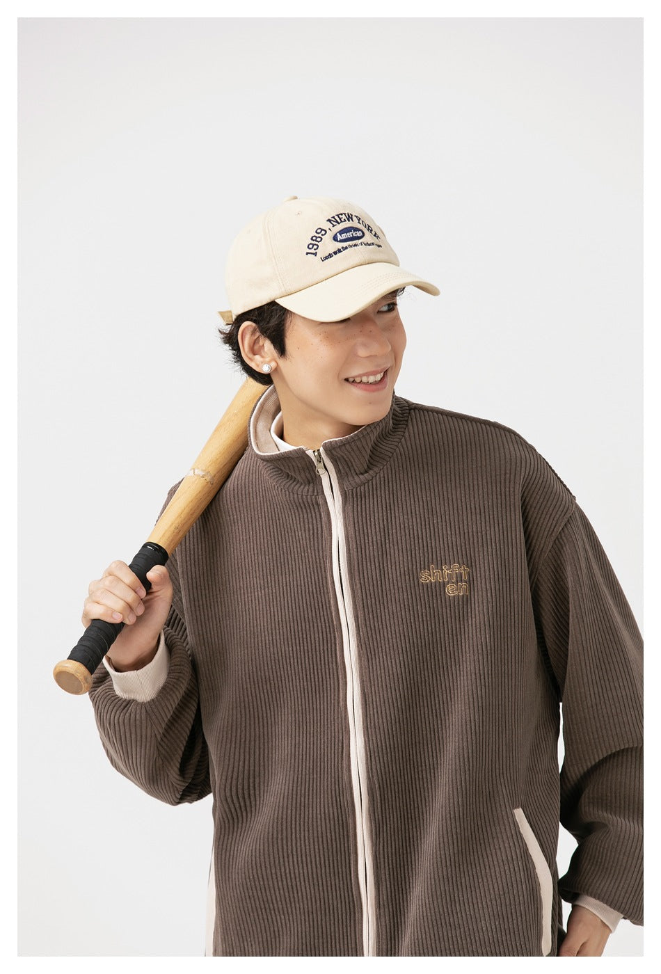 Close view of a model wearing the brown ribbed jacket with cream zipper and embroidered chest detail.