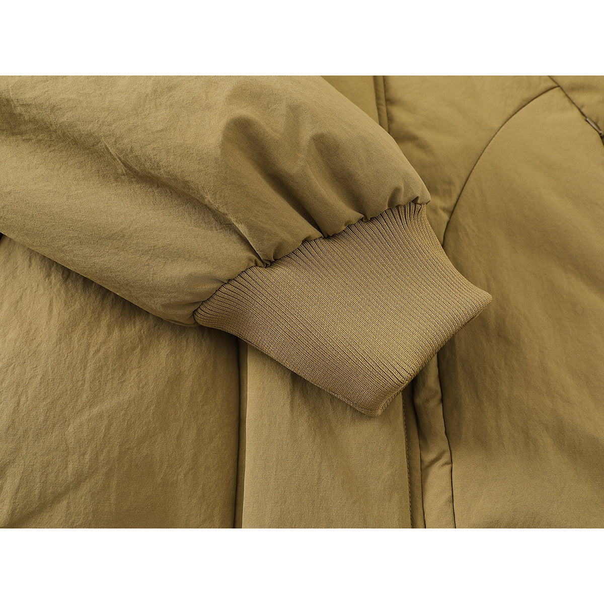 Close-up of a tan jacket sleeve gathered above a wide ribbed cuff.