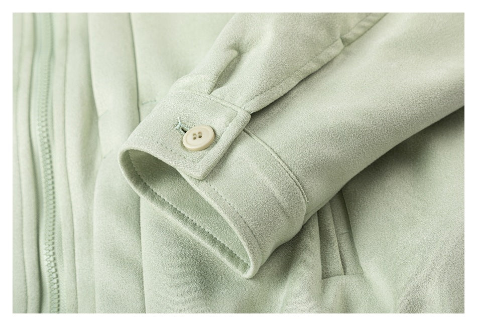 Close-up of a pale sage-green sleeve cuff with a cream button beside the front zipper.