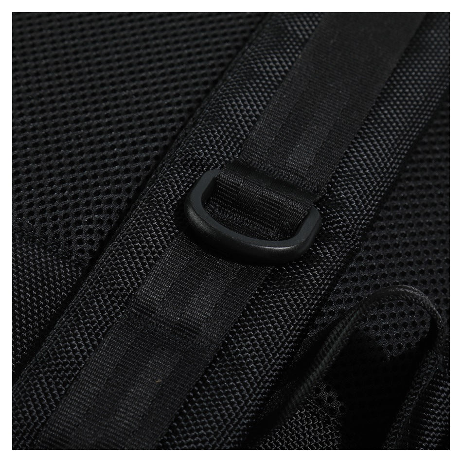 Close-up of black backpack shoulder strap with a D-ring and mesh panel texture
