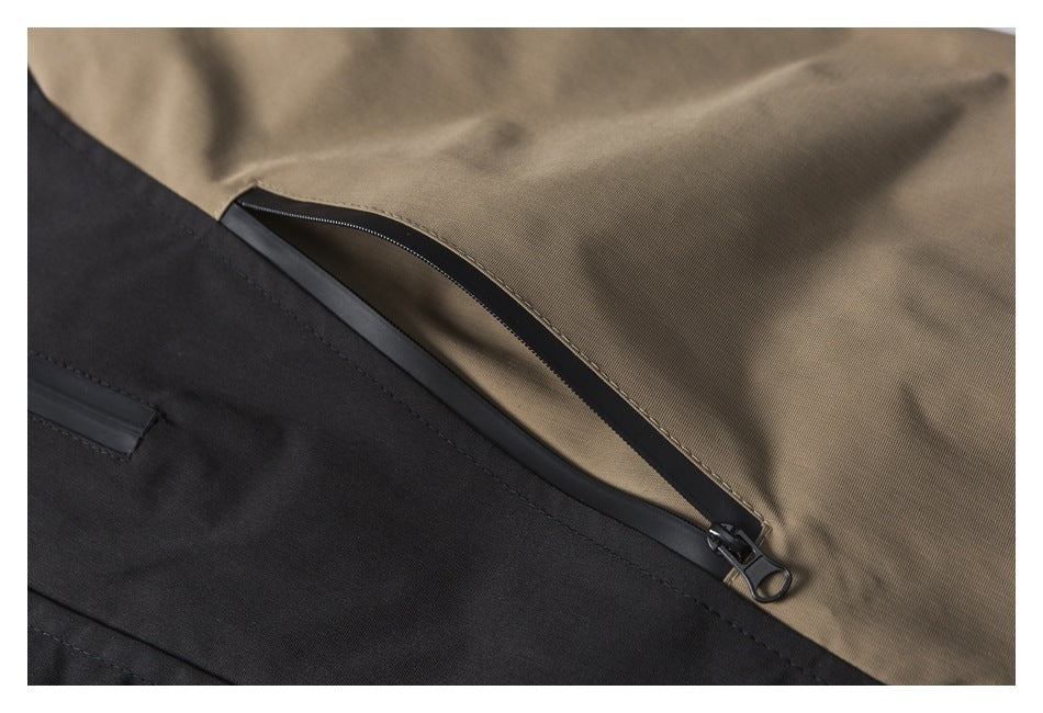 Close-up of a black and tan jacket showing a curved zippered pocket.
