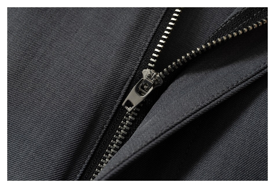 Close-up of a metal zipper and dark charcoal fabric on the trousers.