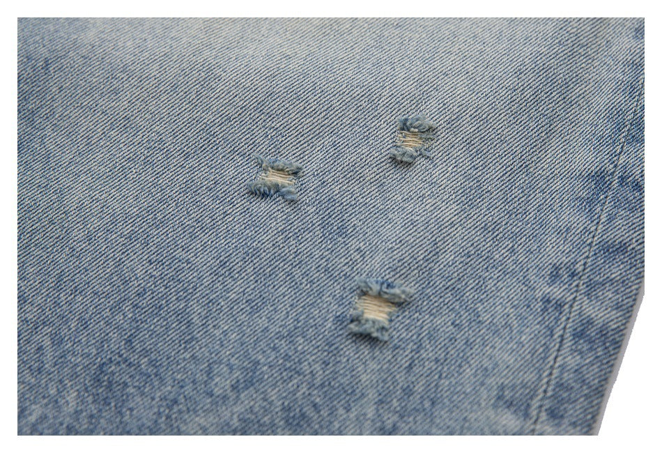 Close-up of three small frayed distress marks on light-wash blue denim.